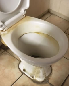 Toilet bowl with heavy limescale and staining before deep cleaning