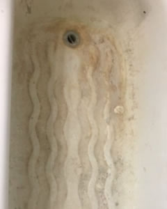 Stained bath base with rust marks and grime before cleaning
